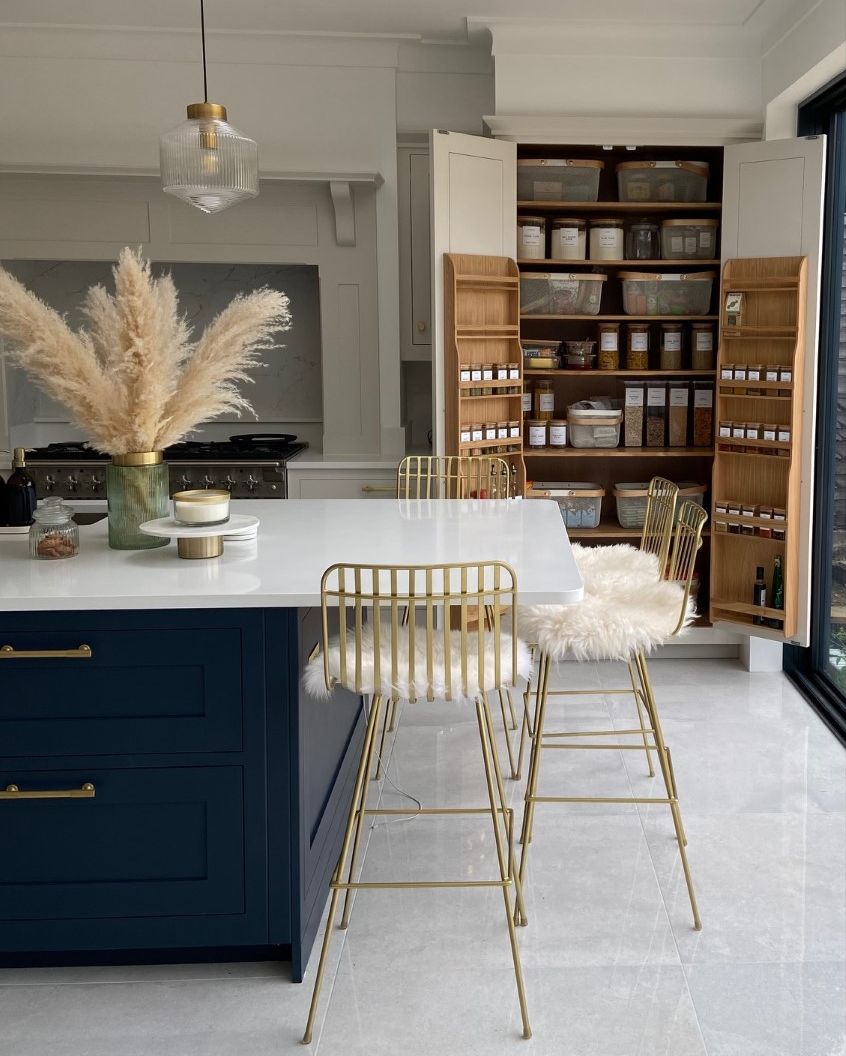 The kitchen of dreams. We love how this deep blue kitchen island, offset by light flooring and worktops, creates a beautifully elegant living space, whilst the gold décor accents add a subtle contemporary edge.