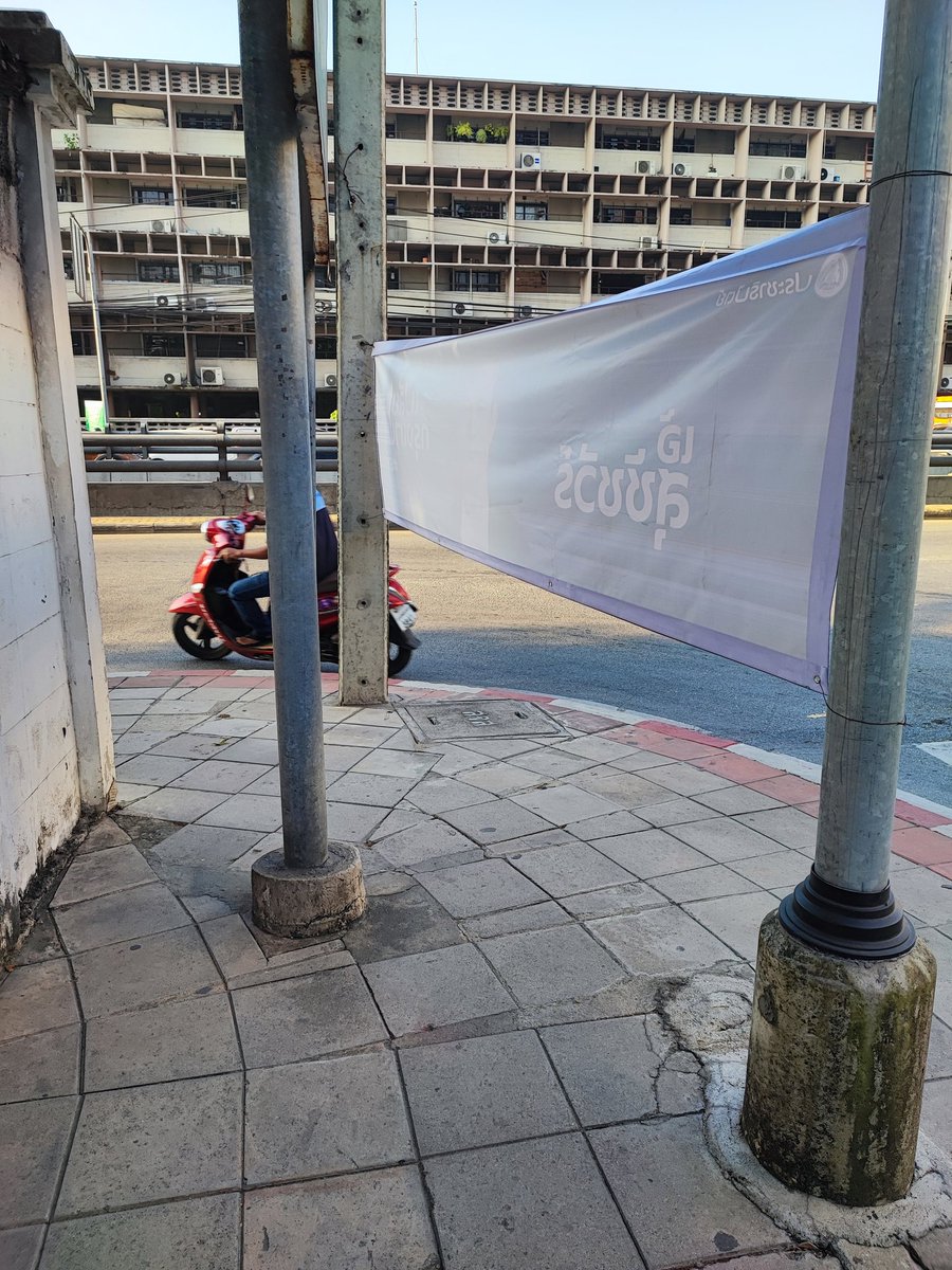 เห็นแค่ข้างหลังยังรู้เลยว่าไวนิลหาเสียงของใคร ก็ติดหัวมุมถนนที่คนเอาไว้เดินข้ามทางม้าลายไปเลยสิคะ