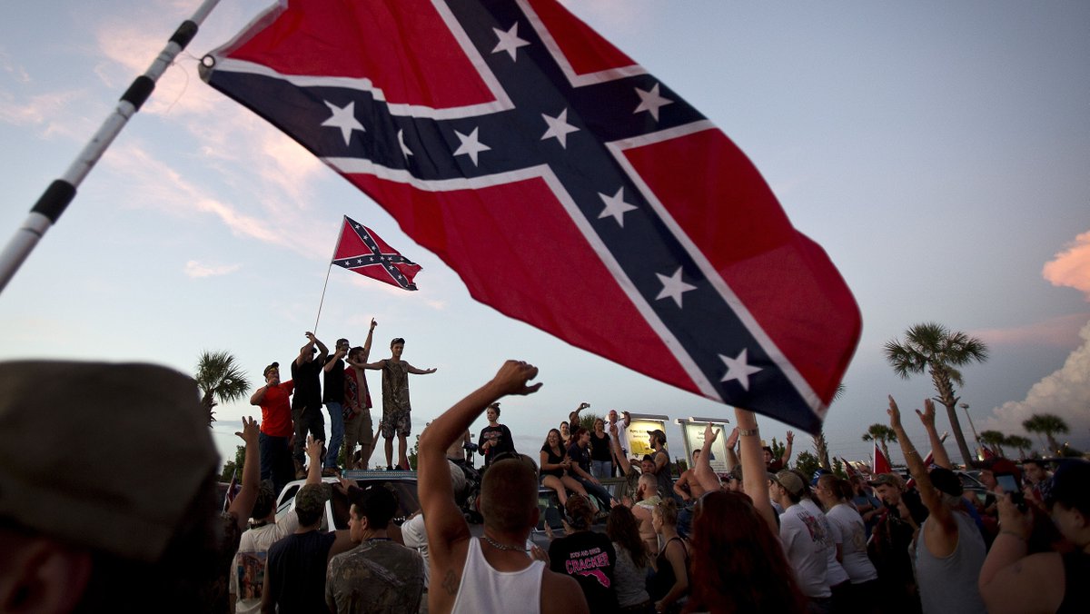 Participants in the "Ride for Pride" event stand on the back of their pickup truck as they speak to an assembled crowd during the impromptu event to show their support of the Confederate flag.