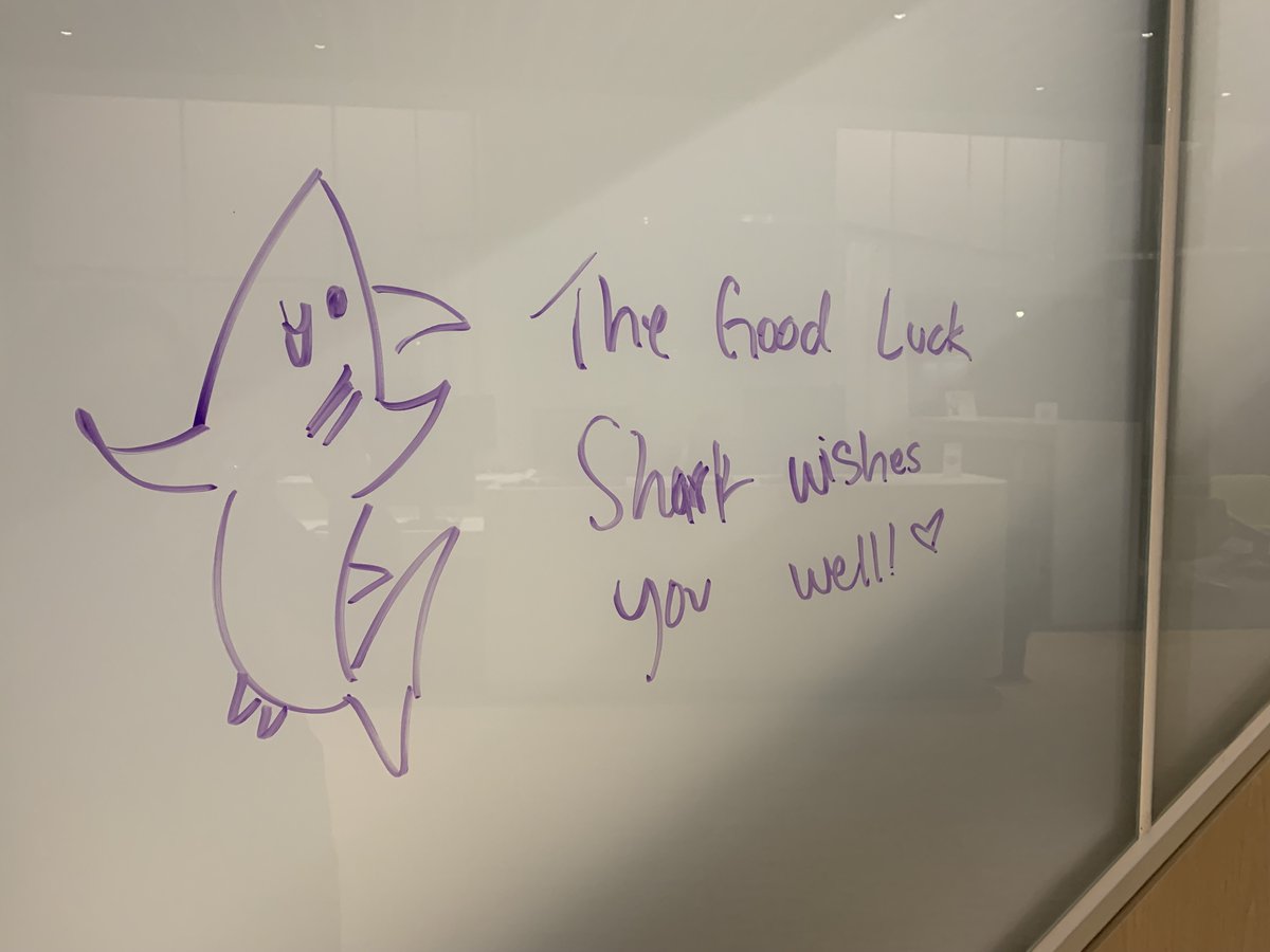 A sketch of a shark on a glass railing with the words "The Good Luck Shark wishes you well!" and a heart