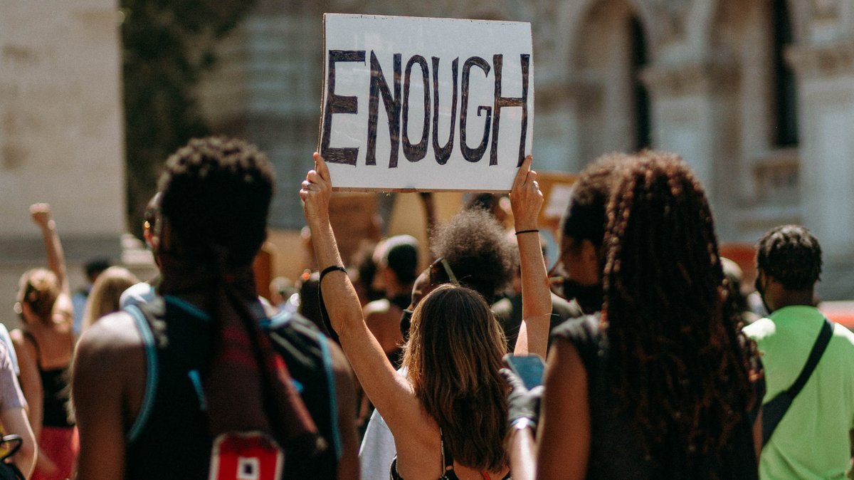 A woman holds up a sign saying 'Enough' during a protest march against racism in 2020.