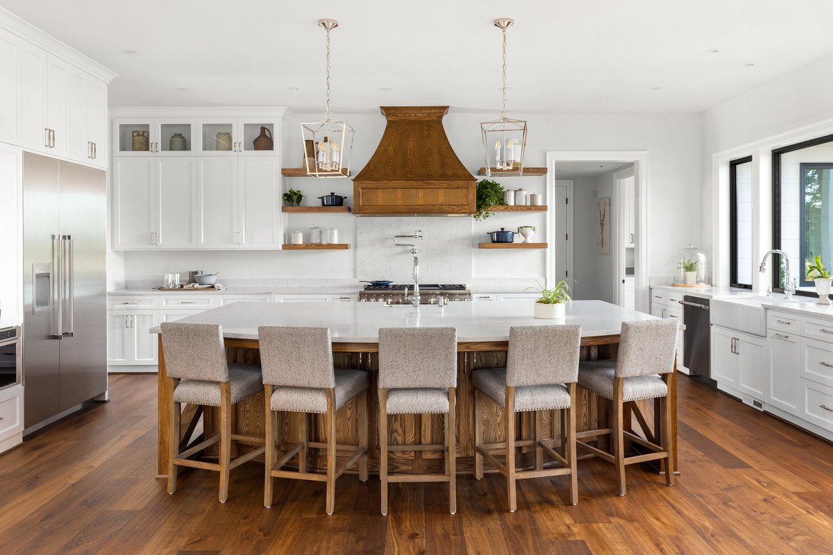 This white and wood kitchen is stunning in all the right ways. White shaker profile doors. Chrome hardware. Pot filler. Marble counters and backsplash. Farmhouse sink. This kitchen combines modern farmhouse, country contemporary, and traditional in more ways than one.