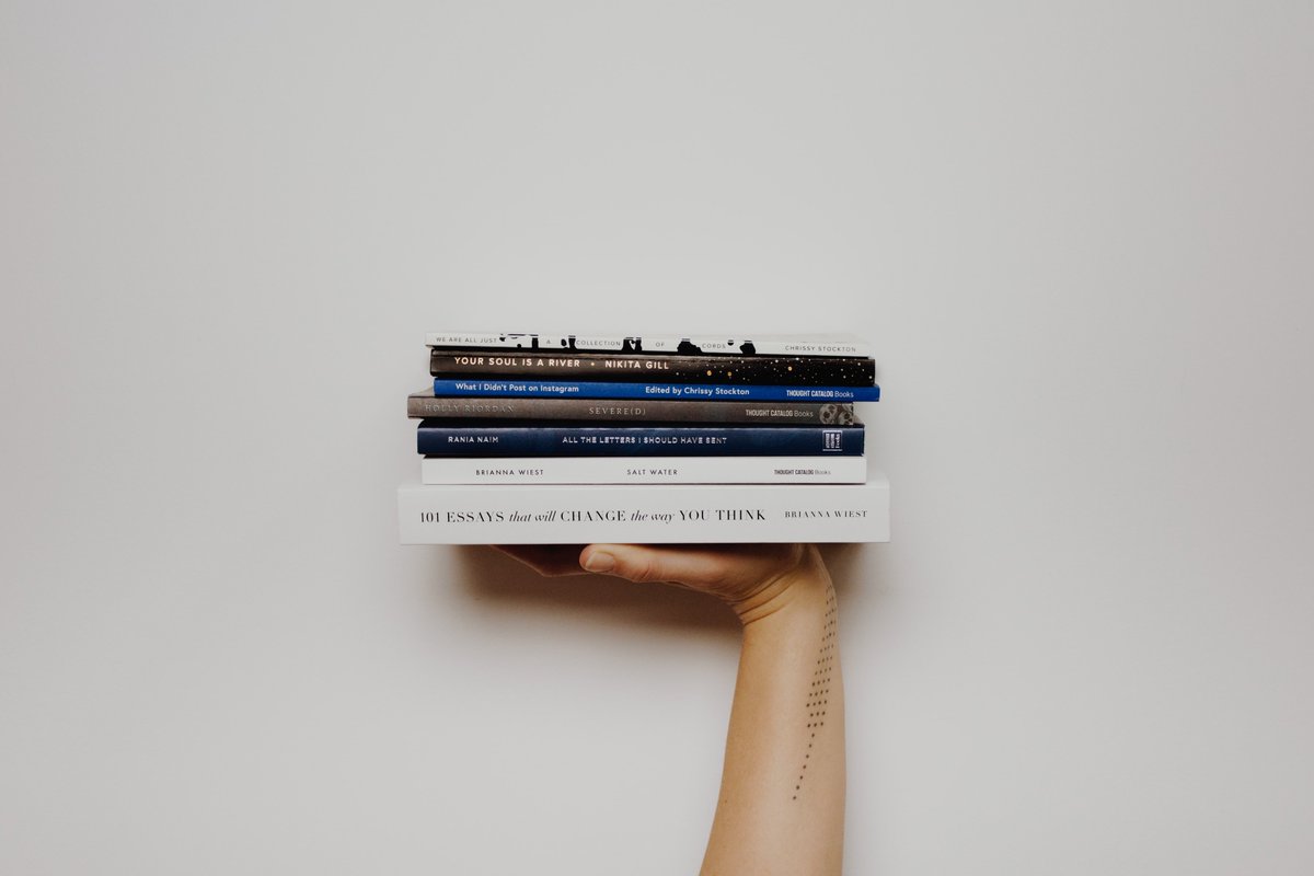 photograph of a small pile of books being held aloft by a hand
