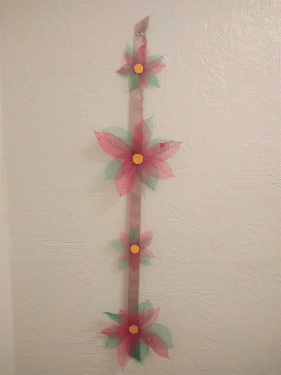 SkeletonLeafJTL's tweet photo. The poinsettia wall hanging decoration. Glued the leaves onto gold ribbon and then topped off with some yellow card for the centre. Large poinsettias are made of 10cm green and 6cm red leaves. The smaller ones are 6cm green and 4cm red. https://t.co/ps1u31ZjXg