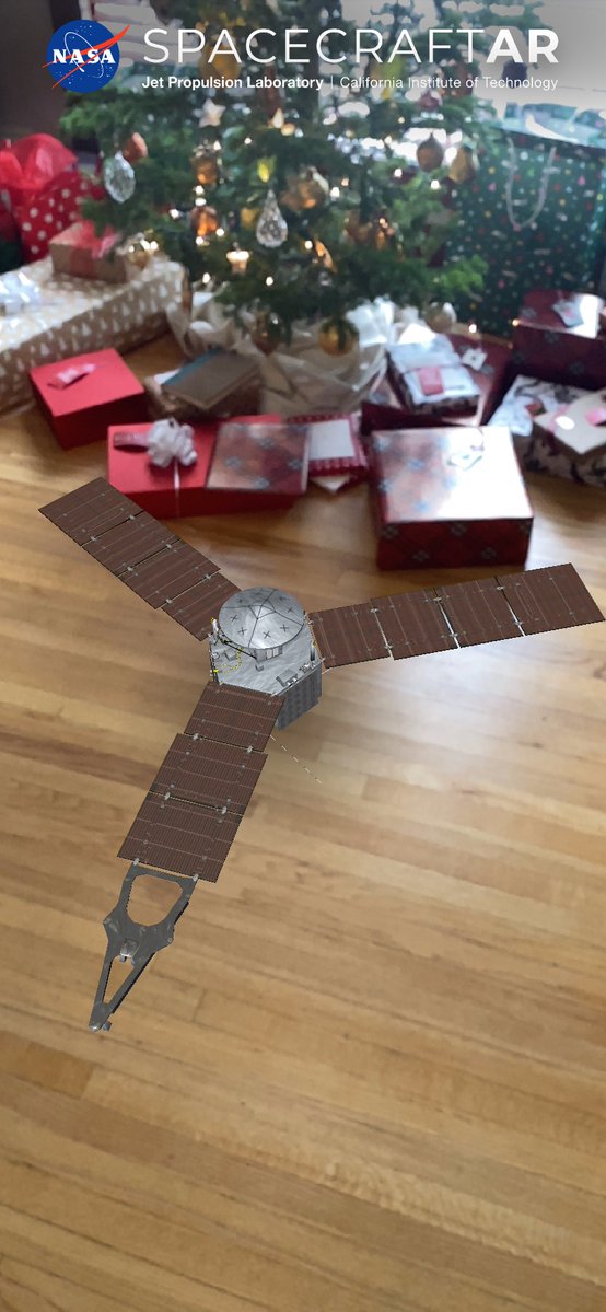 screenshot of mobile device app showing a 3D model of the Juno spacecraft superimposed into a photographed space with gifts beneath a Christmas tree
