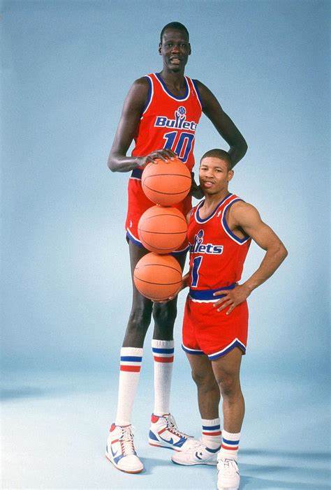 Criação Criativos - Esse é Manute Bol, o jogador mais alto da história da  NBA, com 2,31 metros de altura. Ao lado dele está Muggsy Bogues, o menor  jogador de basket da