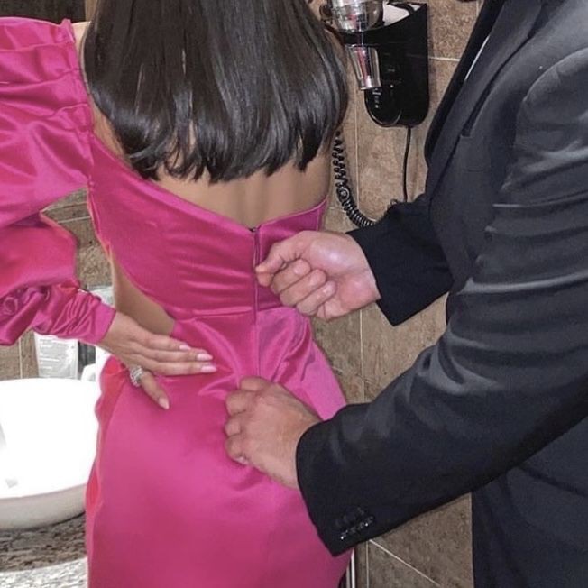 nico finishing up zipping (this is the second time) elena's dress to go to a new year celebration