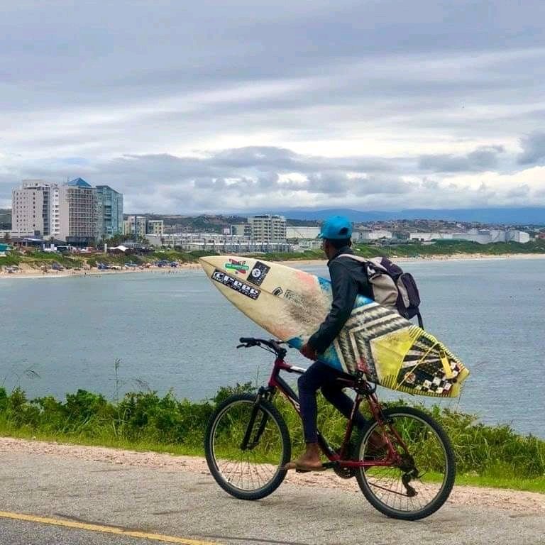 Surfer on a bicycle with a surfboard on the left hand side. Rolling waves and endless sunshine. Shanana to our juniour coach, Sandiso Ntosho 🙏🌊🌊😄😁❤. 

#ridingbicycle #sunshine #love #ocean #oceanlife 

We are tied to the ocean it's calling us and we listen and hear 😁.