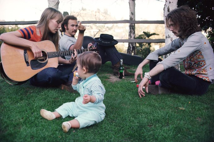 Eric Clapton and David Crosby listening to Joni Mitchell play the guitar in Mama Cass’s backyard, 1968