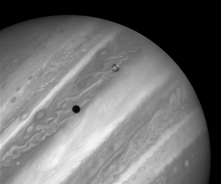 One of Jupiter's moons casts a black shadow across the planet's cloudy surface
