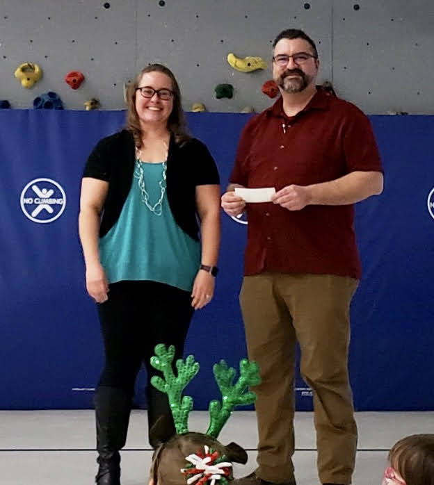 PTO President Erica Pilger delivers a check to Pastor Will Perrigan, the Executive Director of the Norfolk Rescue Mission. Grant Elementary donated $449.76 to the Mission and Pastor Will told the students how the money that they collected would be used to help others.#npspanthers