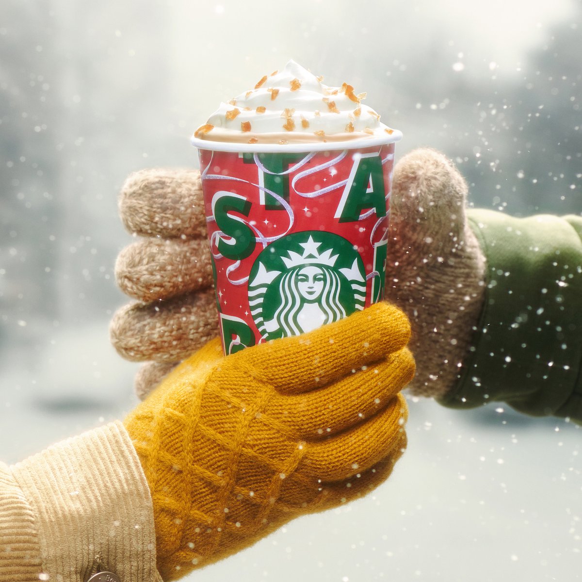 One gloved hand passes a Caramel Brulée Latte to another.
