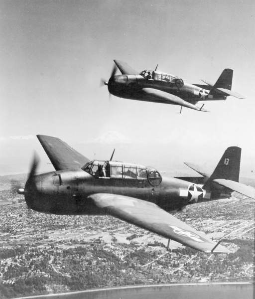 Black and white image of two 286 TBFs flying above a city. 