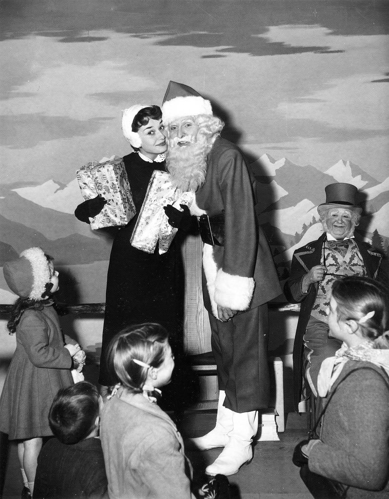 hepburndaily's tweet photo. audrey hepburn helping santa claus hand out gifts to children, 1952 🎁 https://t.co/82dklxz091