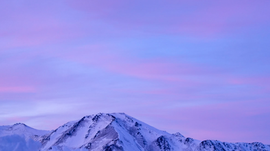 Pink sky over snow covered mountains.