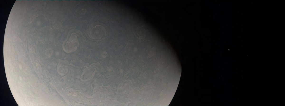 swirling clouds seen on Jupiter, with Io visible nearby as a tiny, yellow dot