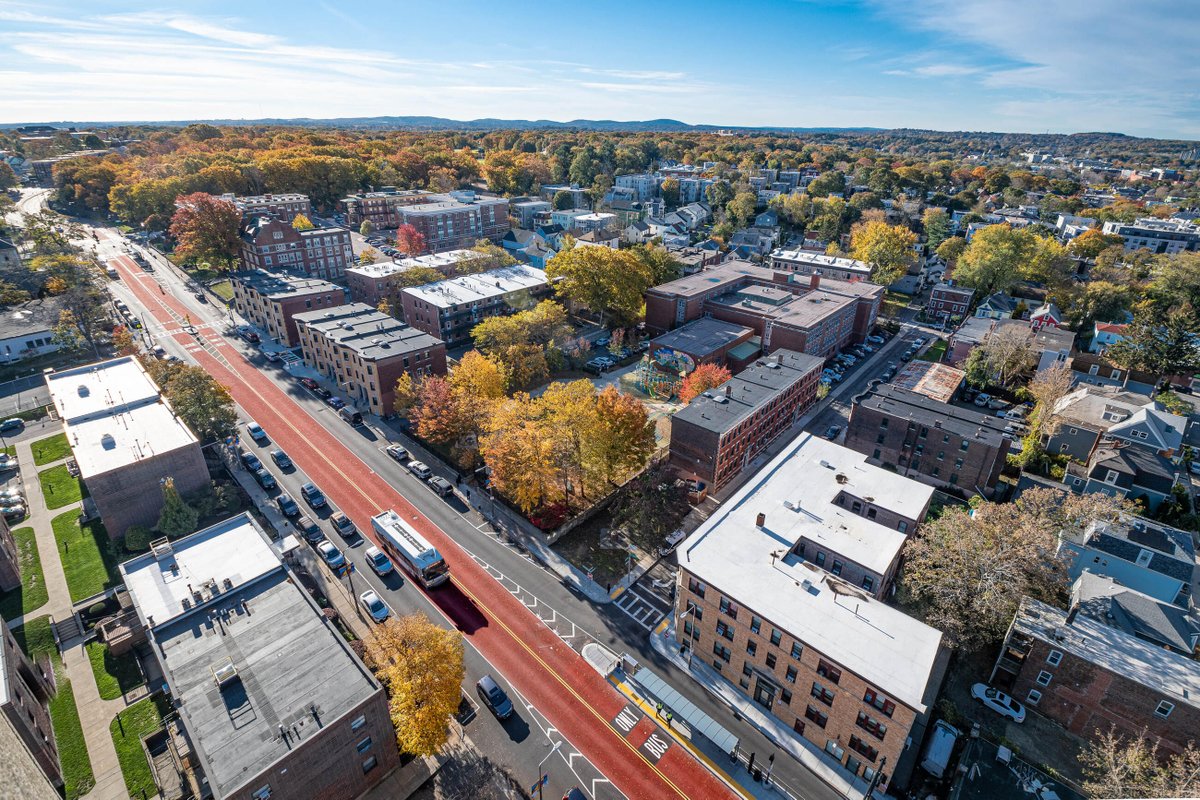 An aerial shot looking down at the red painted Columbus Avenue center-running bus lane in Egleston Square, Boston with an MBTA bus driving down the lane.