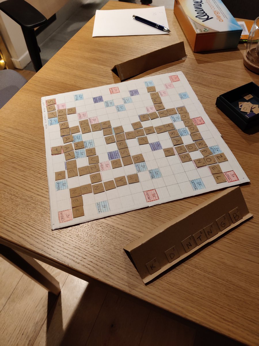 LoicPiret's tweet photo. Day 10 of isolation with my girlfriend. We have made a Scrabble board out of an old pizza box. We even made the little letter holders. @scrabble #boardgames #cardboardgames #upcycle https://t.co/IZE4DwmKy6