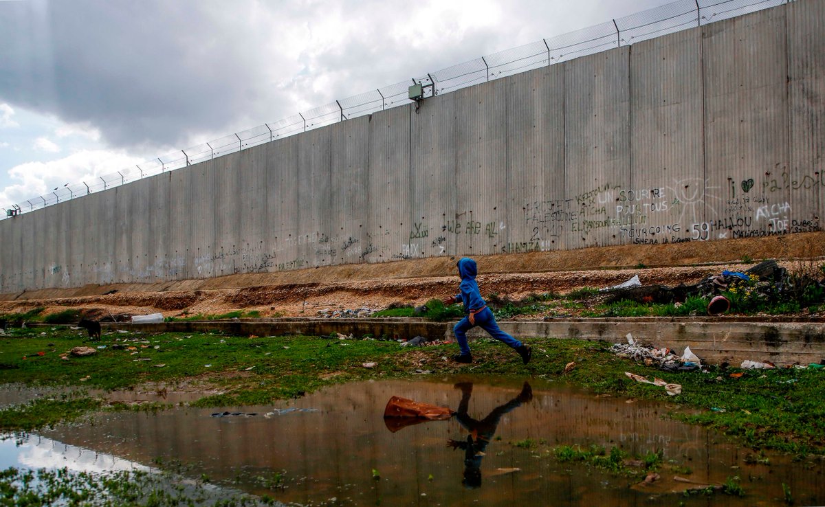 A Palestinian boy runs near Israel's separation barrier in the city of Qalqilya in the Israeli-occupied West Bank. The barrier entirely encircles the city, which is home to more than 55,000 Palestinians.