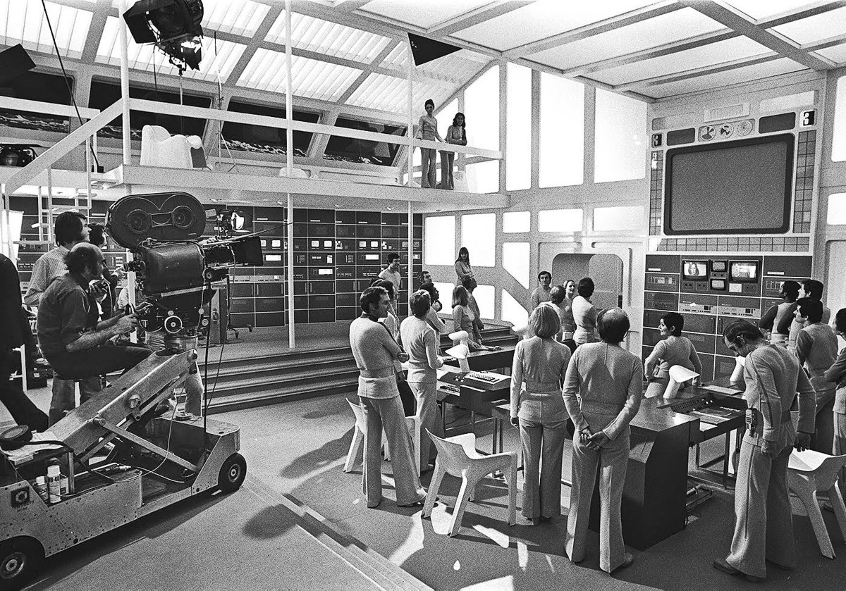 AmericanCine's tweet photo. #ACArchive: At the time, the sci-fi series Space: 1999 (1975-’77) was the most ambitious TV program ever produced in England. Working at @PinewoodStudios, DoP Frank Watts, BSC set the tone with crisp, clean lighting. Here, cast and crew set up a scene on the Moon Base Alpha set. https://t.co/gnWPbtbxiB