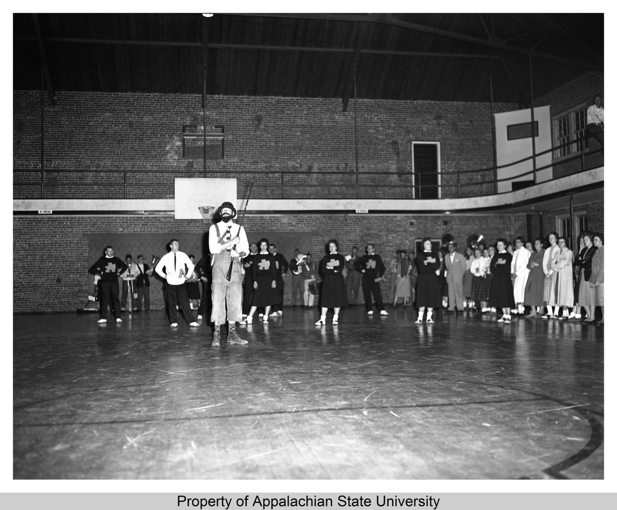 AppStateSCRC's tweet photo. In another look at the history of @AppState mascot Yosef, a 1958 photograph depicts the Mountaineer with a bowler hat, cutoff overalls, and a rifle. Yosef accompanies the Cheerleading squad at a Pep Rally in this vignette. https://t.co/4wrlxtXXUi