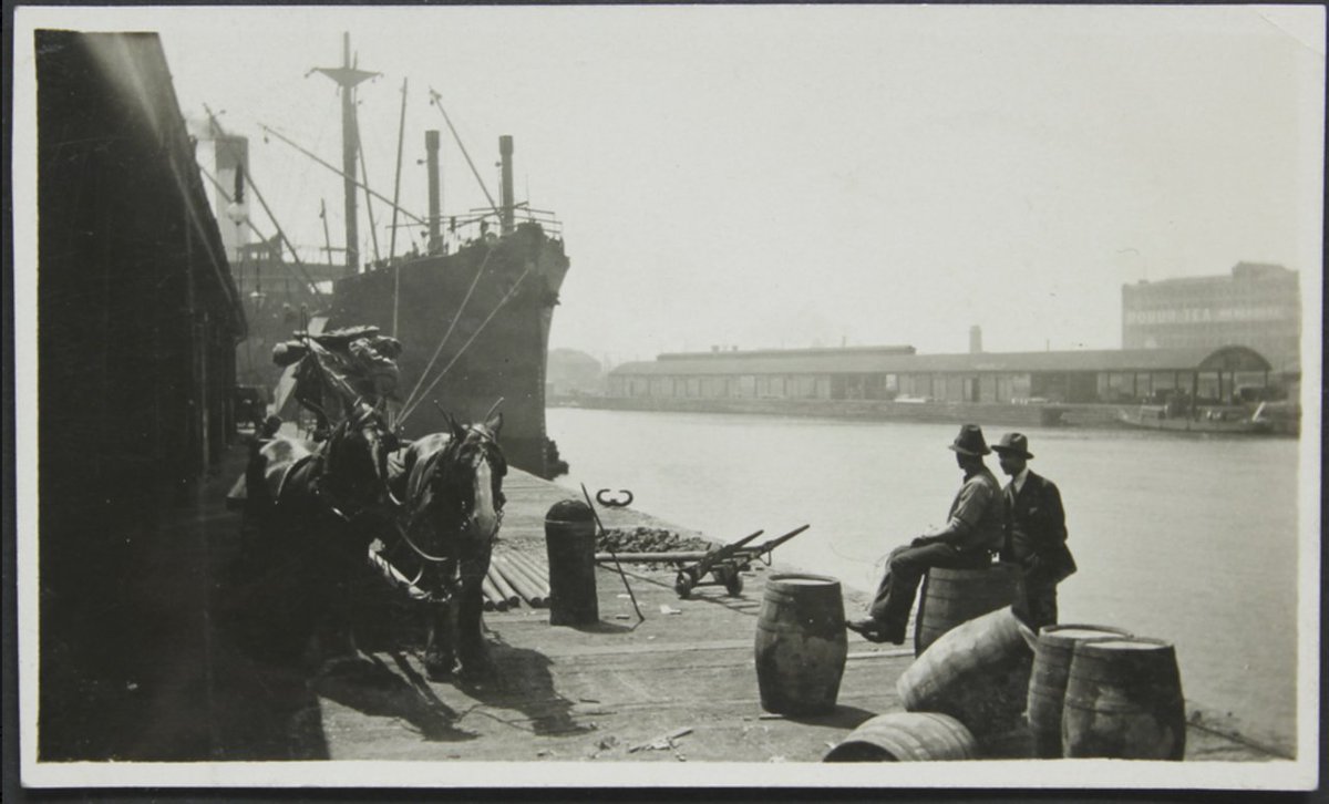 #Throwback Thursday. From our collection, taken on the #Yarra side of the #Mission. Australia Wharf - horses, steam ship, &amp; two men. Across the river: @SouthWharf docks &amp; the Robur Tea House.
It still stands as a reminder of shipping in the past. 
 #Melbourne
#Shipping
#Heritage