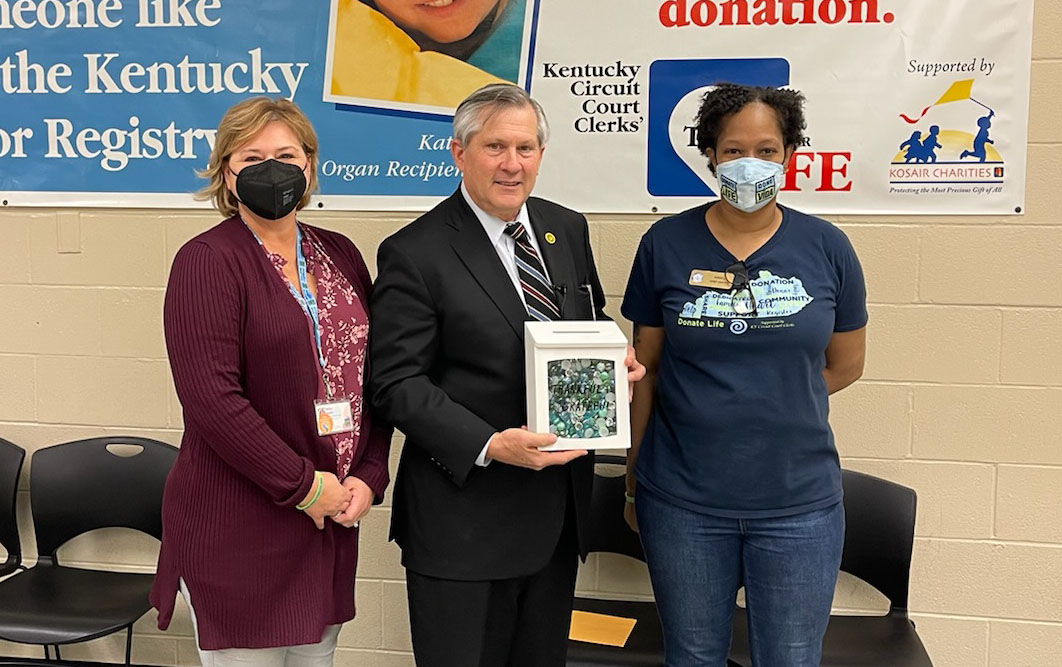 LouKyCourtClerk's tweet photo. End of an Era: Pleased to personally issue the last driver's license at our Bowman Field Branch as @KYTC has assumed operations at all locations in Jefferson County. Honored to receive special gift celebrating organ donation from @DonateLife_KY. @kentuckycourts @KACo @drivekygov https://t.co/hCr6x3Oxyd