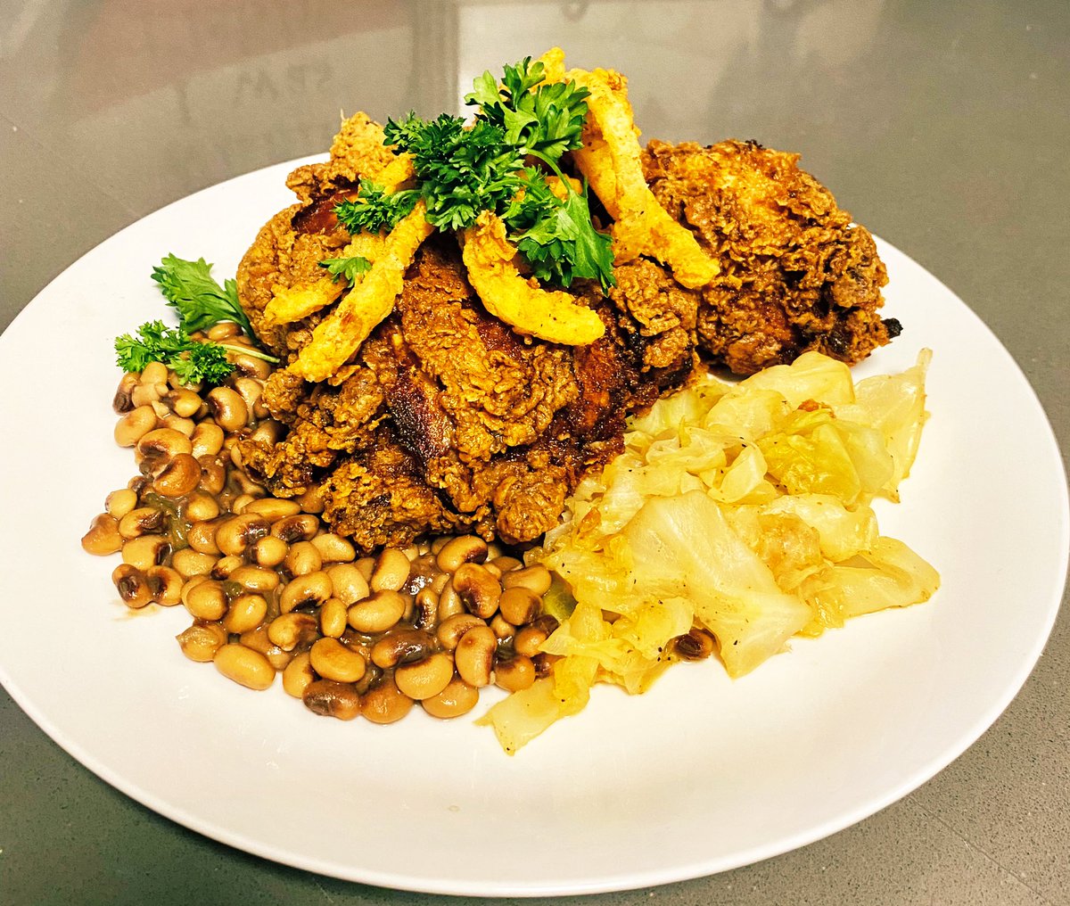 craiggers5's tweet photo. Buttermilk fried chicken, black eyed peas and cabbage topped with homemade onion rings. Wishing everyone good luck and prosperity in 2022. 

#InTheKitchenWithCraig #NewYear2022 https://t.co/nOptxeUE5w