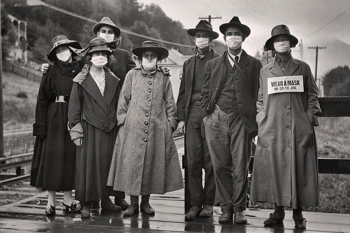 gdmorewood's tweet photo. ‘Rail commuters wearing white protective masks, one with the additional message “wear a mask or go to jail,” during the 1918 influenza pandemic in California.’ https://t.co/pz3E5Cb0OI