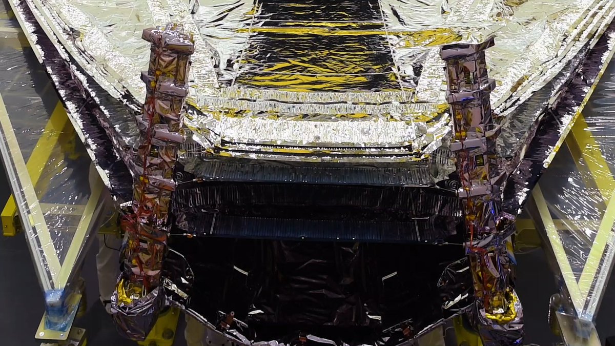 Screen still of the James Webb Space Telescope's sunshield halfway through sunshield tensioning. Two of its five silver, reflective sunshield layers have been pulled taut.