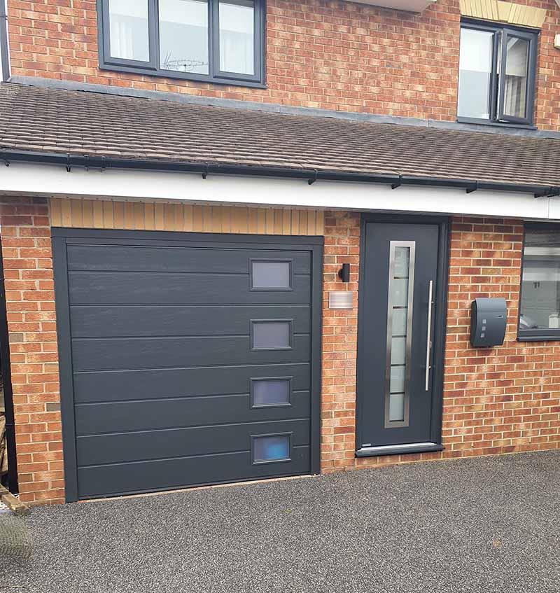 Matching Hörmann insulated medium ribbed sectional garage door with Hormann steel entrance door in style 700B finished in matching anthracite grey.
#Hörmann #garagedoors #doors