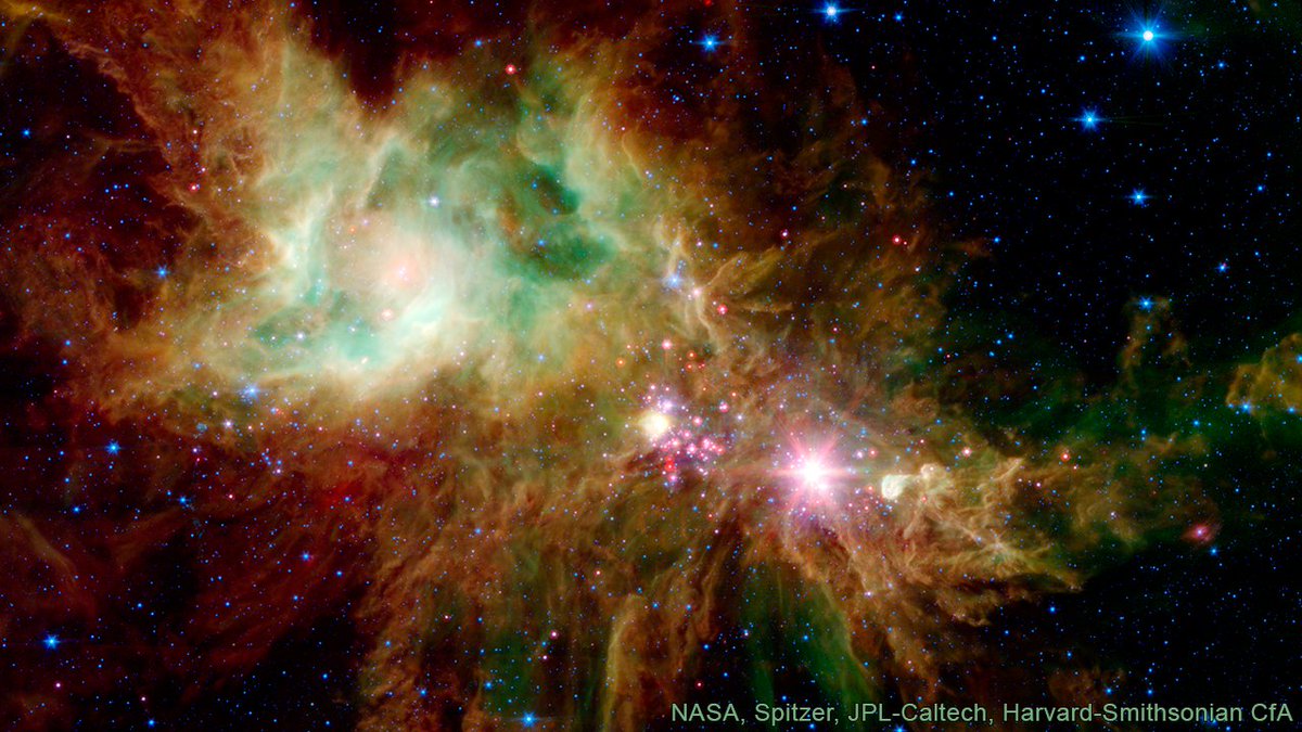 Newborn stars, hidden behind thick dust, appear as pink and red specks toward the center of this infrared image. The stars appear to have formed in regularly spaced intervals along linear structures in a configuration that resembles the spokes of a wheel or the pattern of a snowflake.