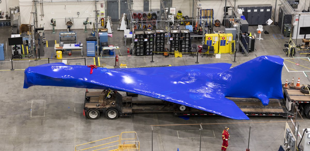 X-plane on ground inside facility entirely wrapped in blue protective material