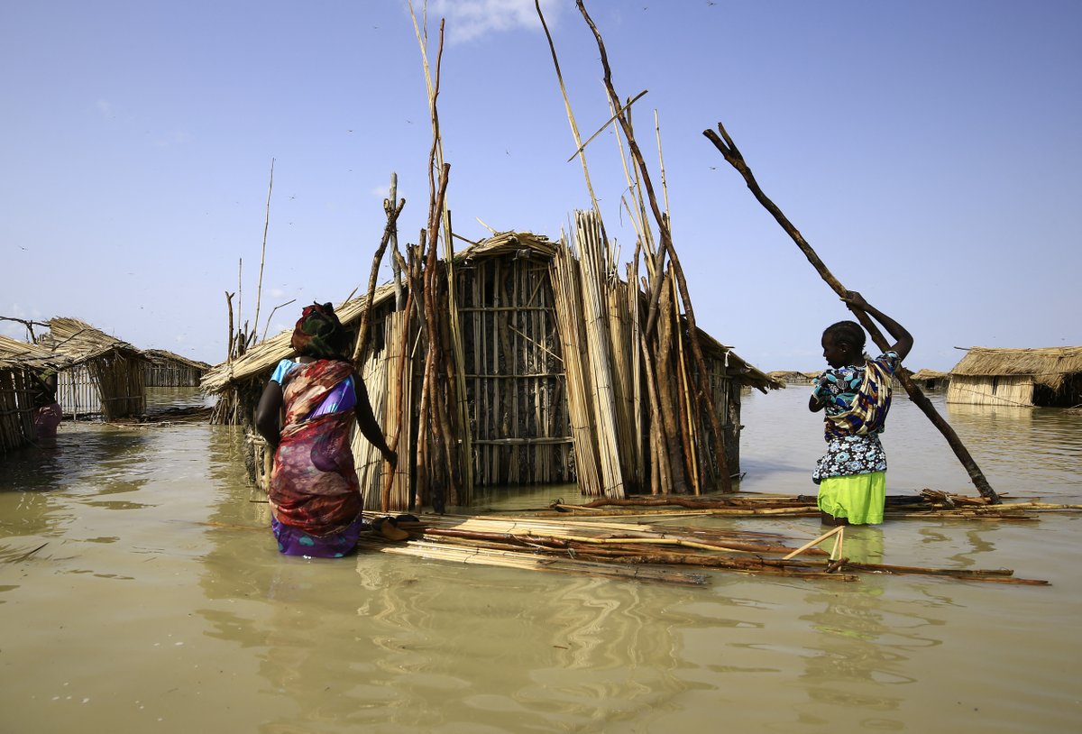 Sudanese refugees try to repair hut amidst flood. Credit: ASHRAF SHAZLY/AFP/Getty Images.