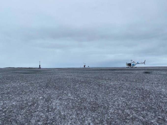 A scientist with PROMIS/GEUS checks instruments on the Greenland ice sheet, 1 September 2021. The ice is darkened by an unprecedented algae bloom caused by persistent cloudy and rainy conditions in 2021 that promoted ice algae growth. Photo: GEUS