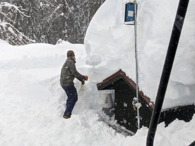 A WSDOT crew member shovels out the radio generator shed from under feet of snow.