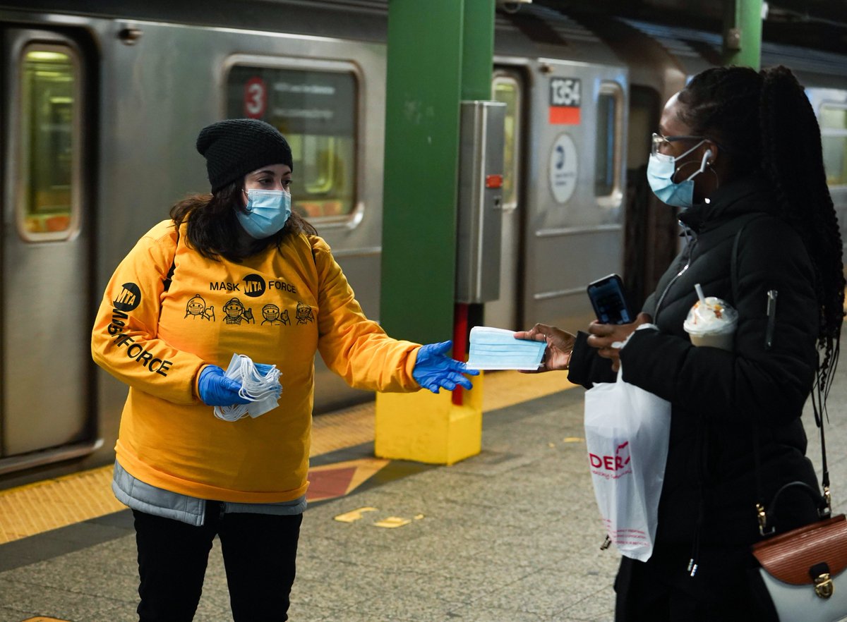 A volunteer hands out a free mask at the Atlantic Av-Barclays Ctr subway station.