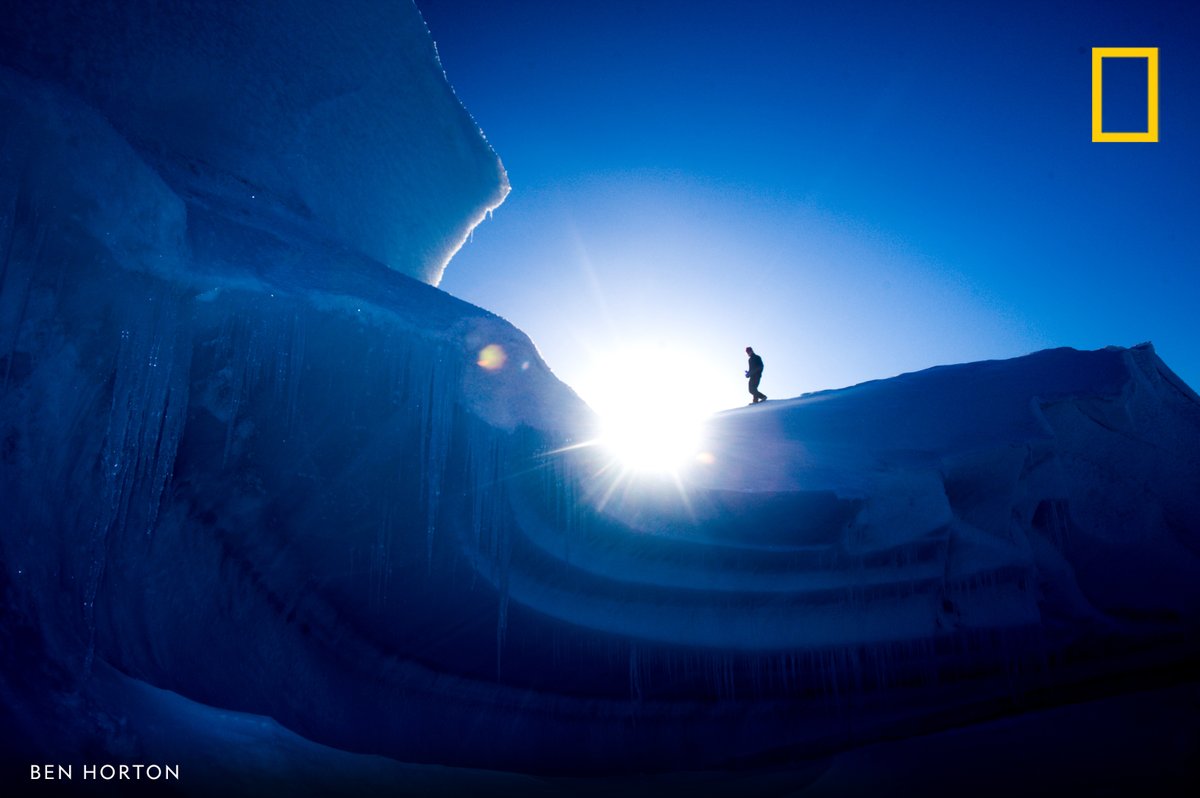NatGeoTravel's tweet photo. A hiker explores an iceberg frozen into the sound near Axel Heigburg Island, Canadian Arctic. https://t.co/IStBUaP6Je