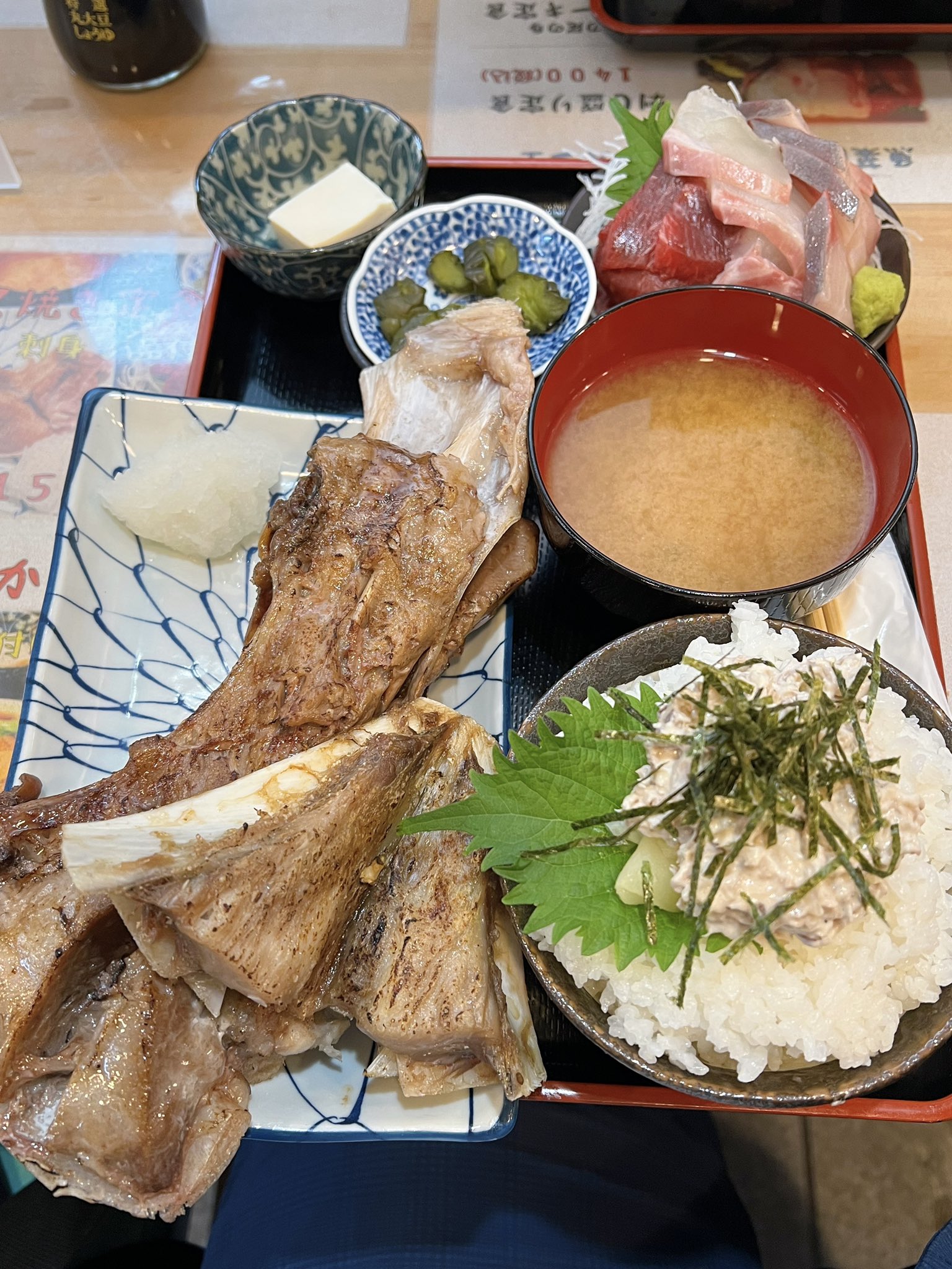 フォーリンデブはっしー 月島 勝どき にある 魚菜はざま のランチで食べられる マグロのカマ焼き定食 1500円 がスゴイ 皿からハミ出る巨大なマグロのカマステーキに 山盛り刺身3種など付いて すんごいボリューム 100円で 自家製ツナマヨ の