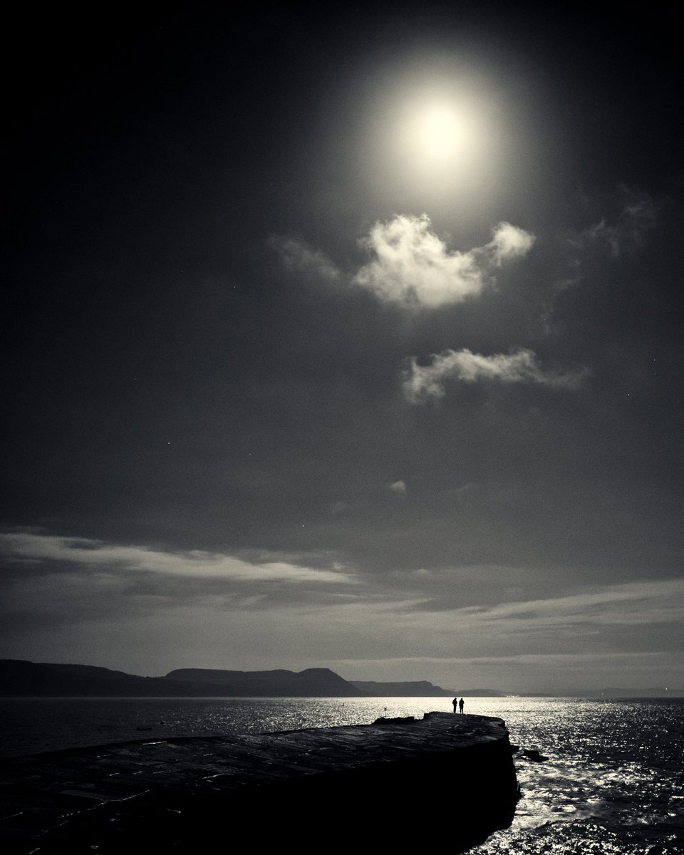 Lyme Regis 2022. The two guys at the end of the Cob were the only two people I saw all evening. It was a beautiful night to be out with a camera. #dorset #lymeregis #blackandwhitelandscape #seascape #nightphotography #documentary #moon #landscapephotography