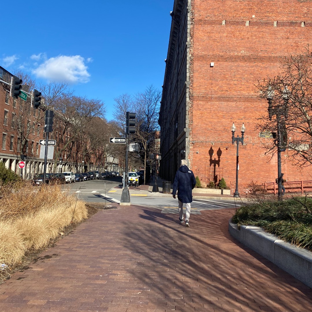 person walking on a wide brick sidewalk into Boston's North End