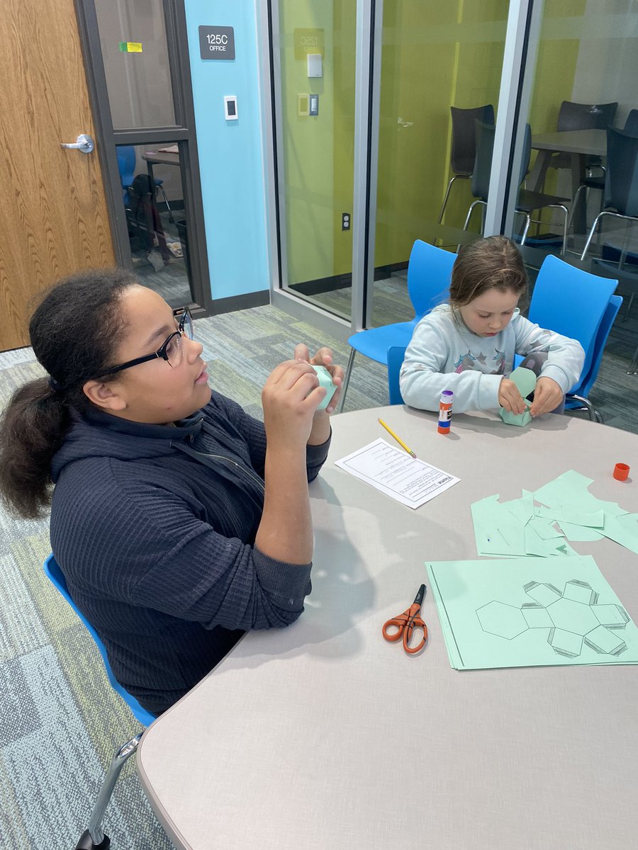 Middle school students mentoring second graders!  Using nets to create 3D shapes.  Love the relationship building! #goodhueschool