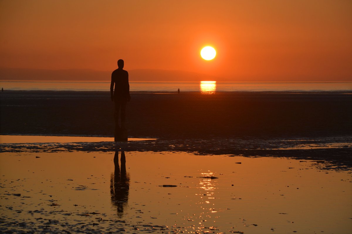RonDaviesPhoto's tweet photo. This has been a wonderful week for sunsets. A magical still evening at Crosby beach today, the sea flat calm, reflecting the light of the sky as the sun’s disc sank below the hazy mountains of Snowdonia. @IronMenCrosby https://t.co/LTILmkKFxR