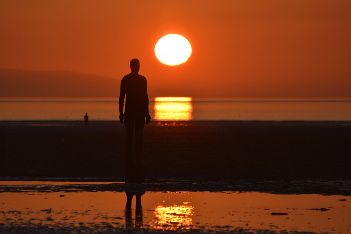 RonDaviesPhoto's tweet photo. This has been a wonderful week for sunsets. A magical still evening at Crosby beach today, the sea flat calm, reflecting the light of the sky as the sun’s disc sank below the hazy mountains of Snowdonia. @IronMenCrosby https://t.co/LTILmkKFxR