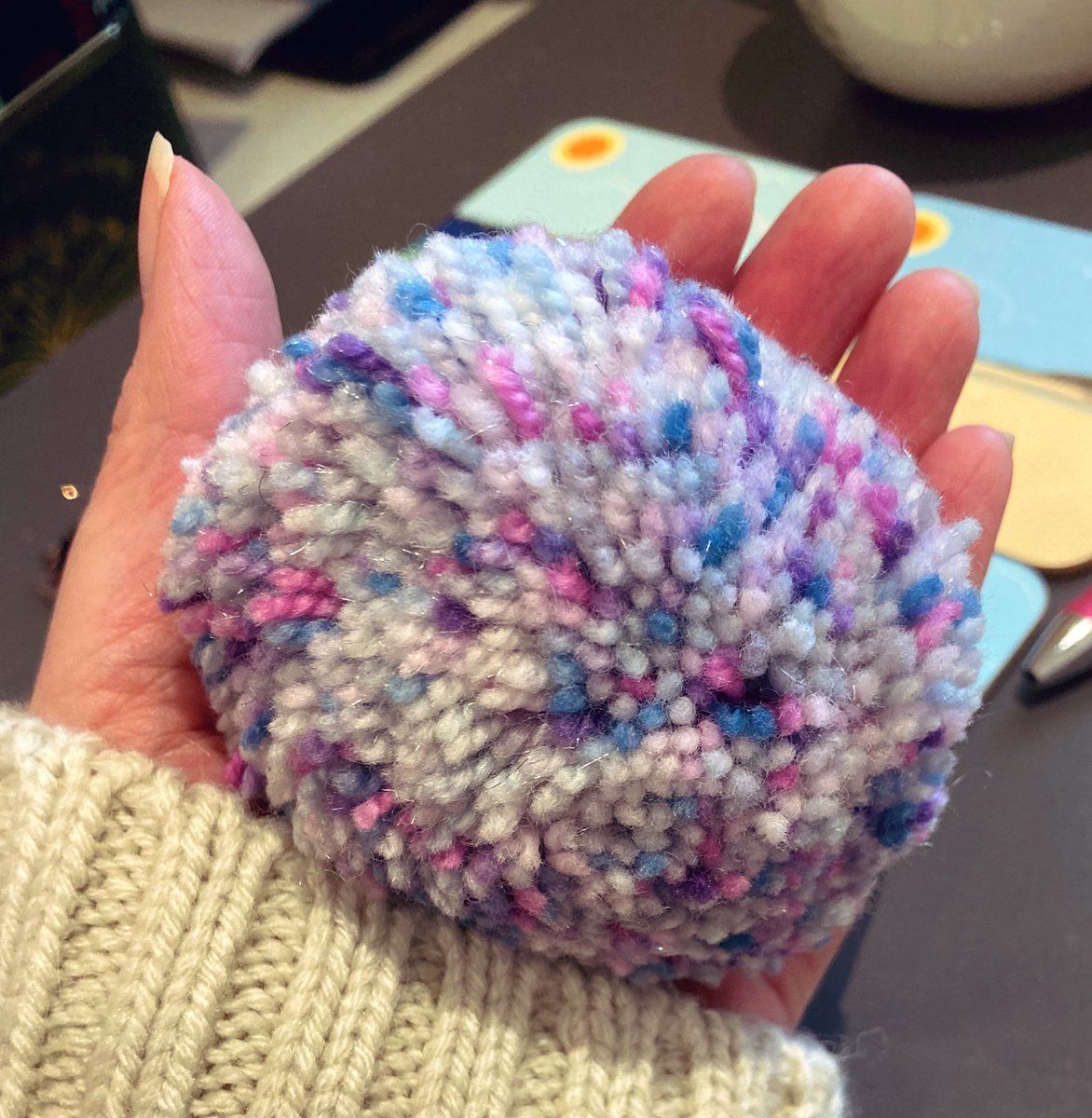 wurdsmyth's tweet photo. Making a note of good things for 2022:

16th Jan - I made this pompom with a remnant of wool during the first lockdown and it’s a lovely, warm, tactile thing to hold when I’m thinking through plot twists at my desk. Also, it’s sparkly!

#GoodThings2022 https://t.co/ZR2AcowyQk