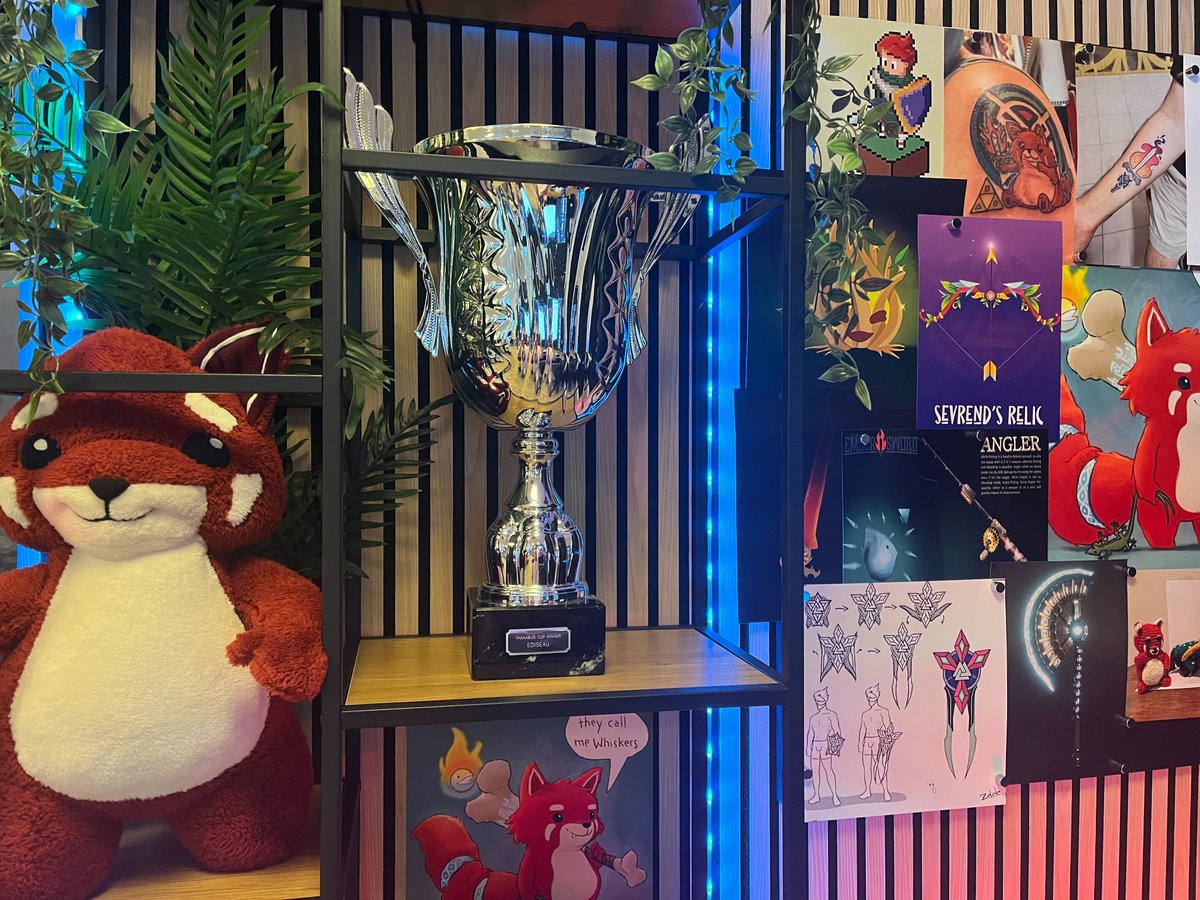 PlayEmberSword's tweet photo. The Thanabus Cup🏆 now proudly displays Ediseau's name! Congratulations again to the winning nation and all of its wonderful denizens⭐

P.S. We could barely keep Whiskers away from it. No matter where we move him, he keeps appearing next to it. https://t.co/RZkFNntcFG