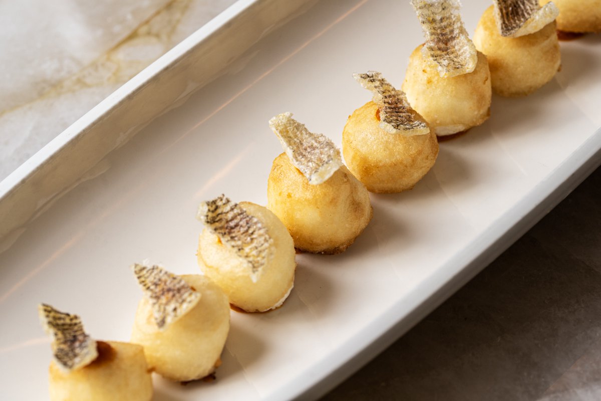 Nuestros buñuelos de bacalao son uno de esos platos que te transportarán a la orilla del Mar Mediterráneo, con una textura suave la explosión de sabor que se produce al masticarlos es inolvidable.