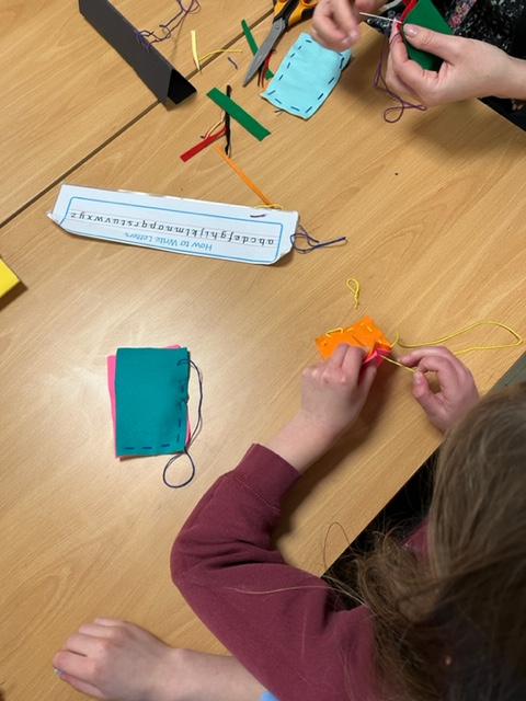 Class 2 have been building on the weaving skills they developed in Year 1 o create a cape for their model superhero. They used a running stitch to join two pieces of fabric together.