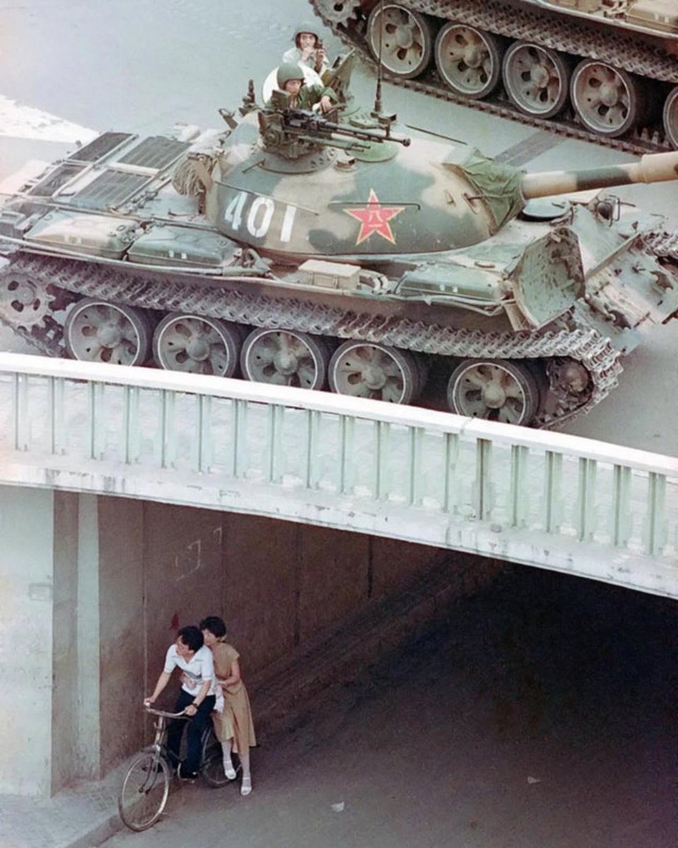tolearnhistory's tweet photo. A couple on a bicycle take cover beneath an underpass as tanks deploy overhead in eastern Beijing in 1989. https://t.co/rQDpjzS8NZ