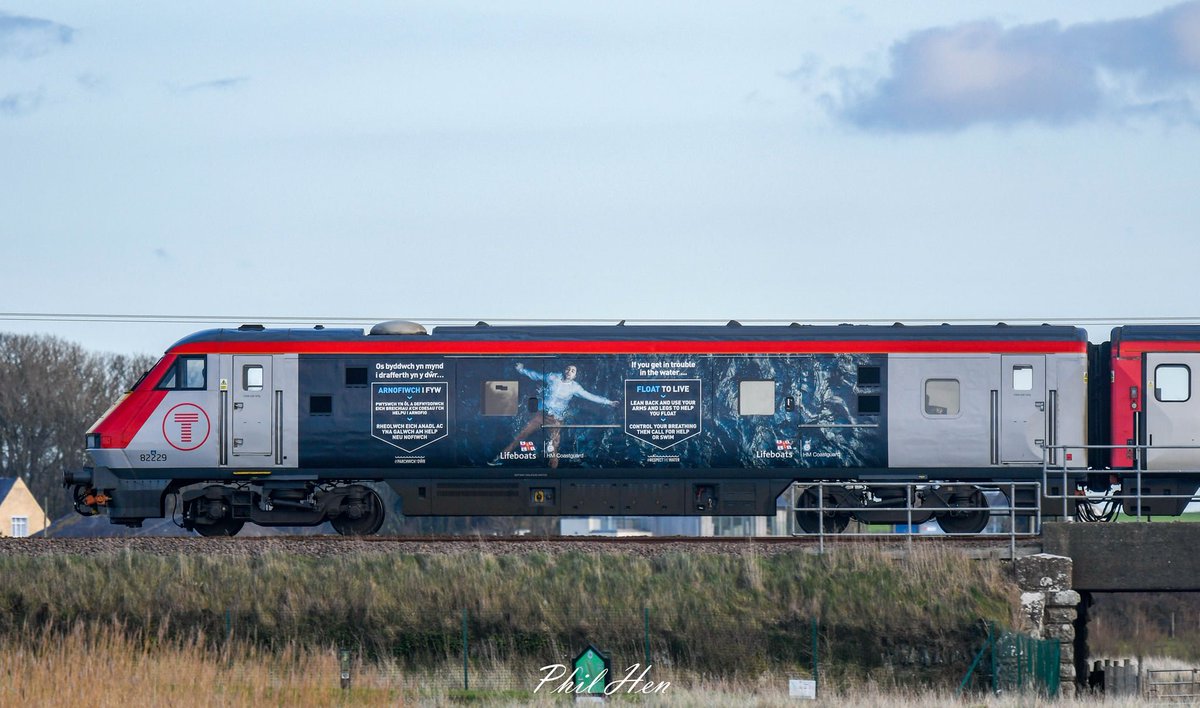 A shot of the RNLI-liveried train as she makes her way past @RAF_Valley towards Holyhead. The @RNLI had won a poll on which charities logo should feature on the @transport_wales train.